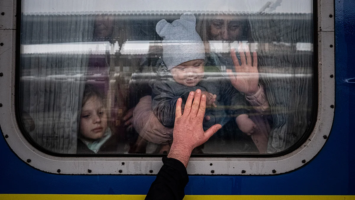 Ein Mann streckt seine Hand an die Scheibe eines Zuges, das Kind und seine Mutter in dem Zug drücken ihre Hand zum Abschied von Innen auf das Glas.