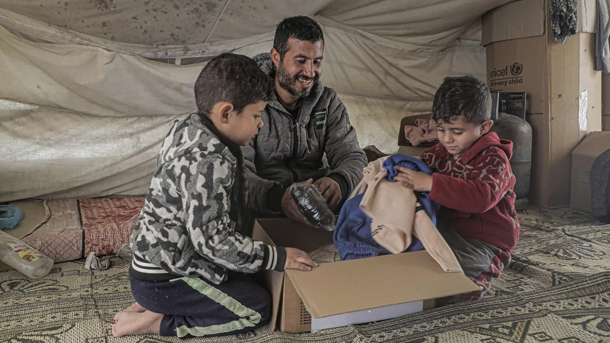 Eine Familie schaut gespannt in den Inhalt einer UNICEF-Hilfsbox.